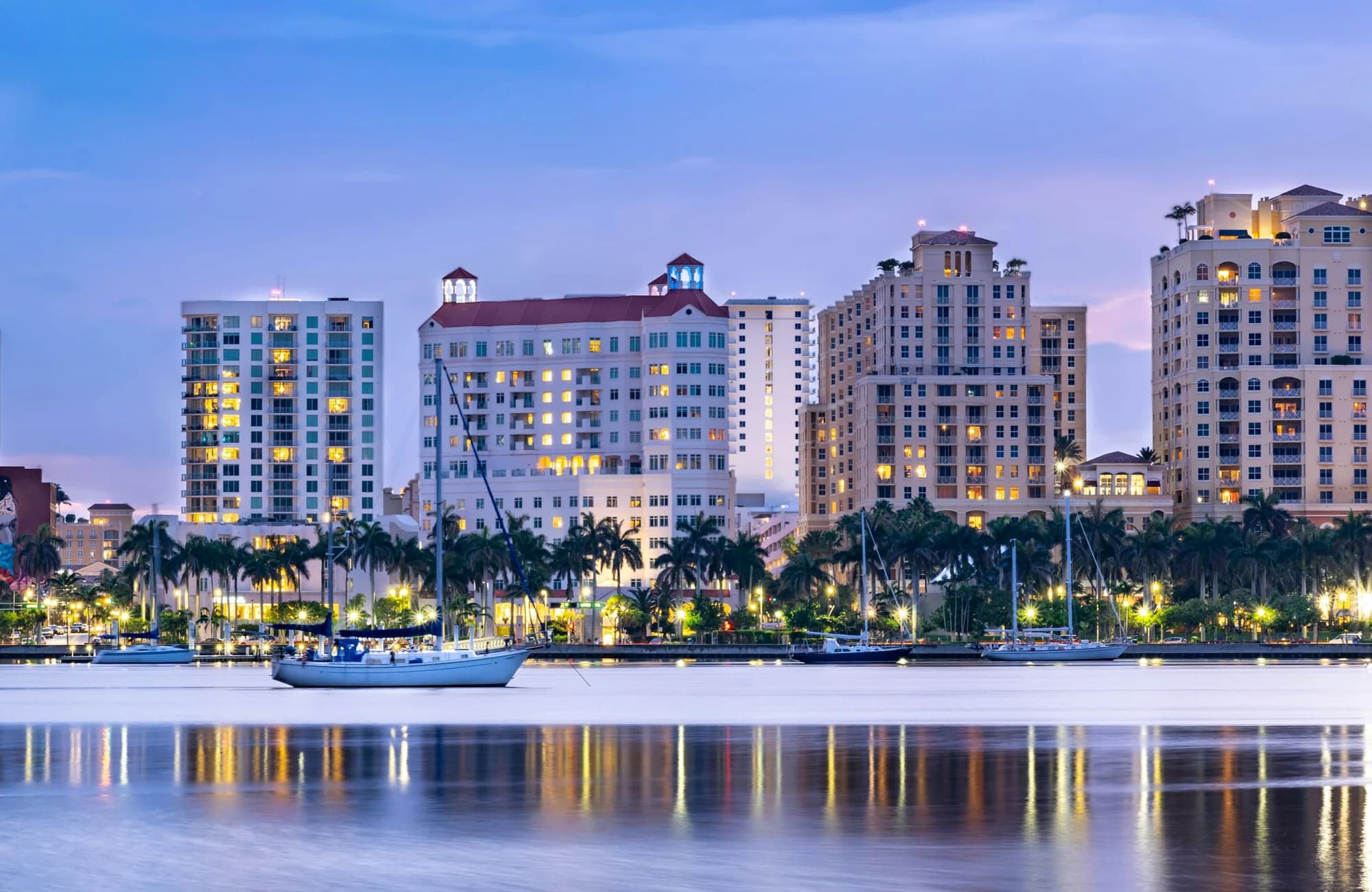 Boats and reflections along the West Palm Beach waterfront at sunset.