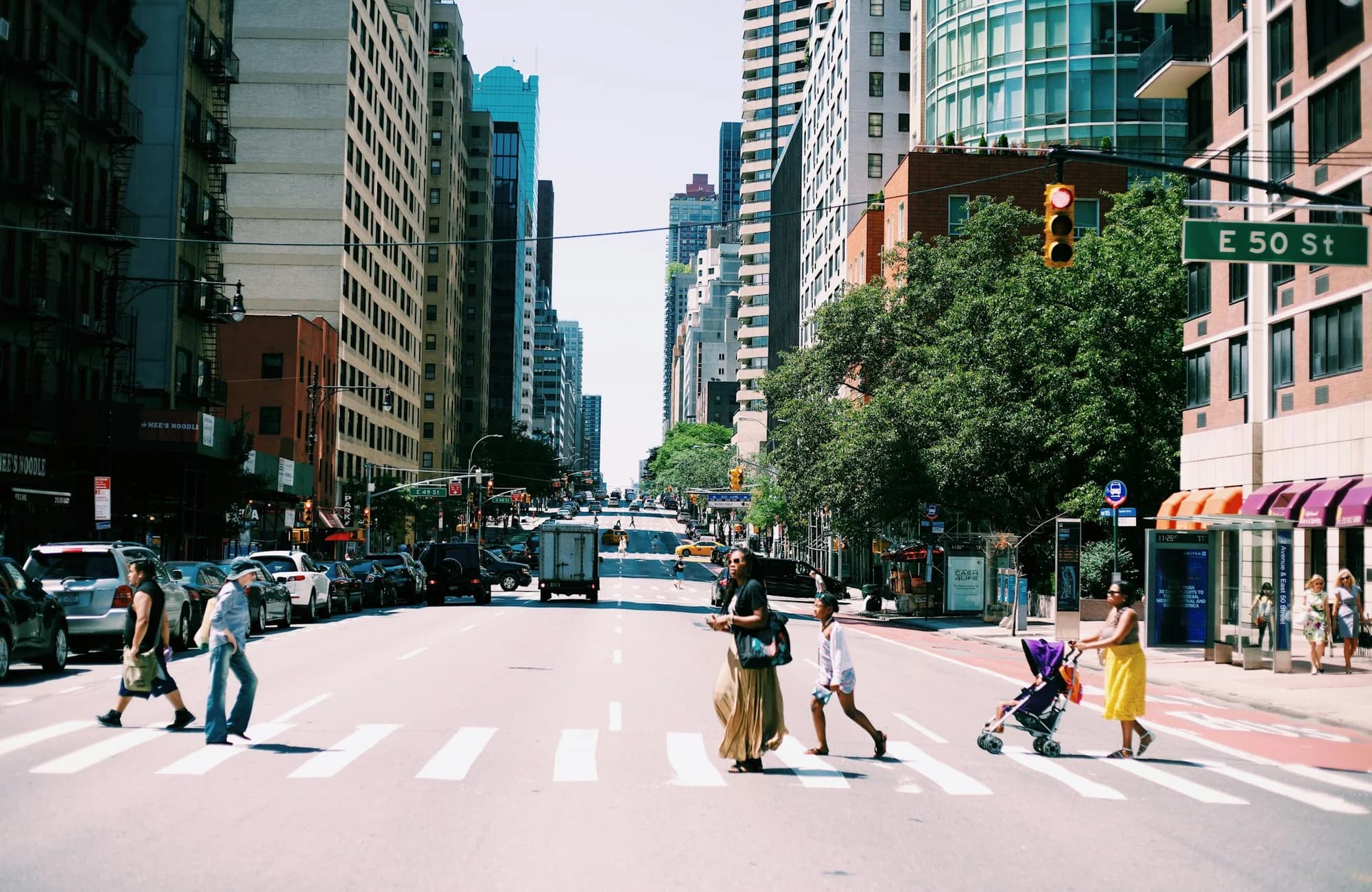 People moving across a busy city crosswalk.
