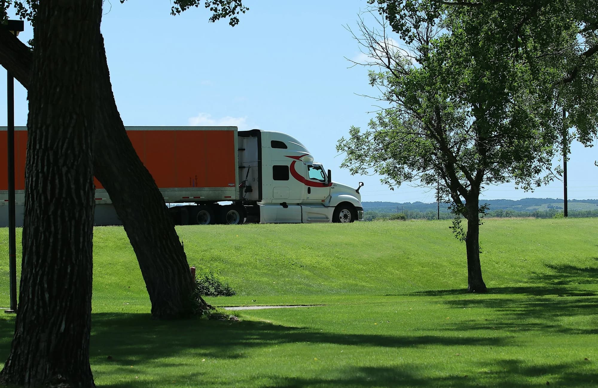 A semi-truck and trailer beside a rural roadside.